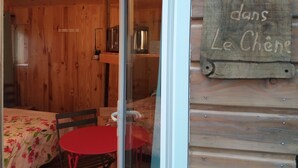 A wooden interior with a bed, a small table, and a sign reading "Le Nid dans Le Chêne".