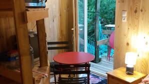 A wooden cabin interior with a bed, a table, and a chair.