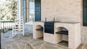 A stone patio with a brick barbecue area and a white chair. - Gorgeous Estate set in beautiful Lancaster County  (Bird in Hand)