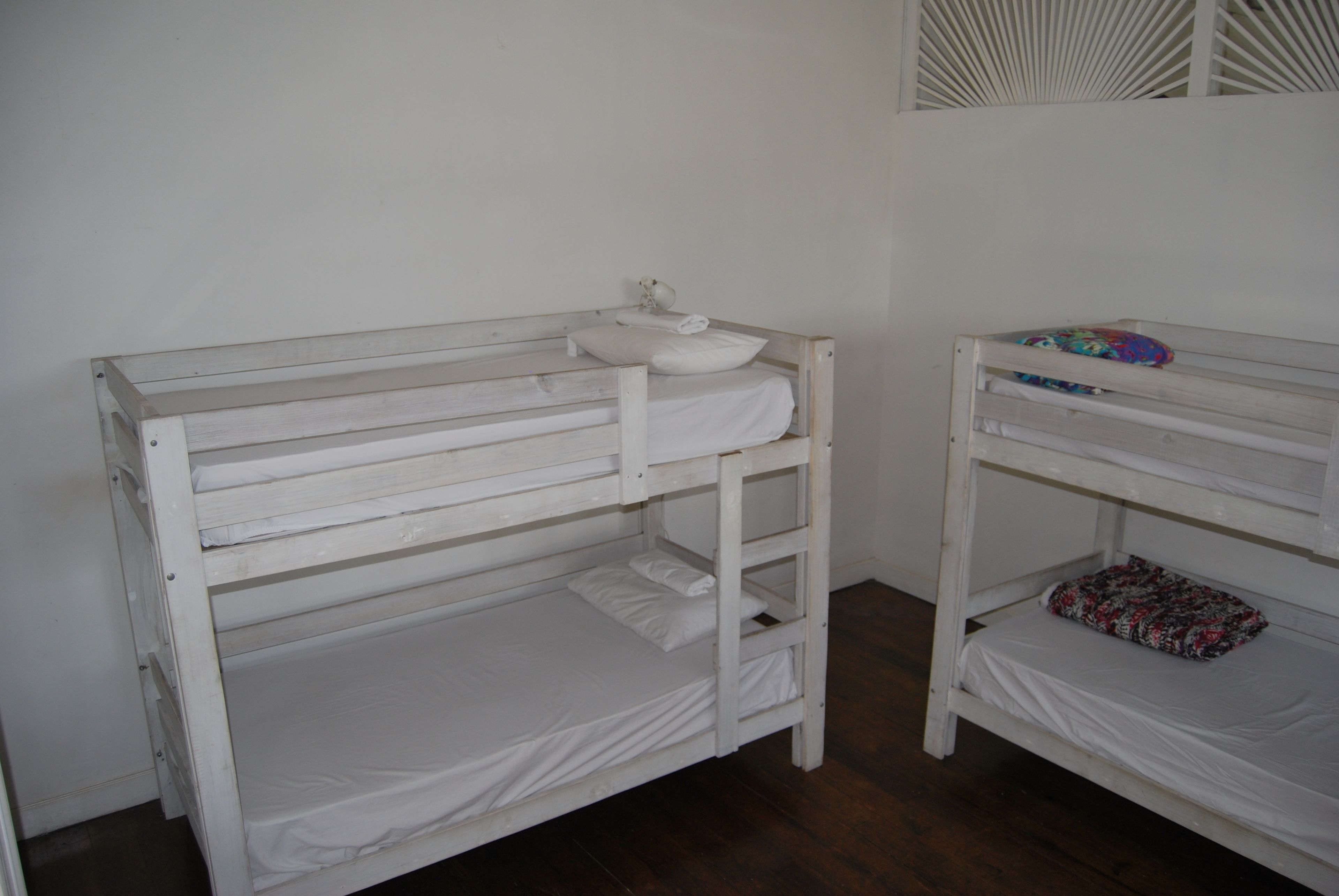 A bunk bed with a white mattress and a pillow on the top bunk.