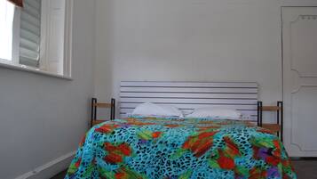 A bed with a colorful floral bedspread, a white pillow, and a wooden headboard.