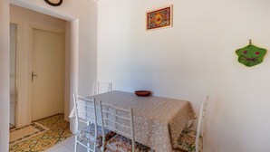 A dining area with a table and chairs, a clock on the wall, and a decorative item on the wall. - Pet-Friendly Studio for Two (Veli Lošinj)