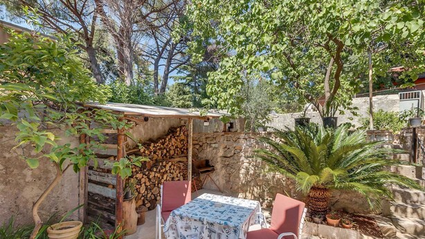 An outdoor patio with a table and chairs, a stone wall, and a variety of plants. - Pet-Friendly Studio for Two (Veli Lošinj)