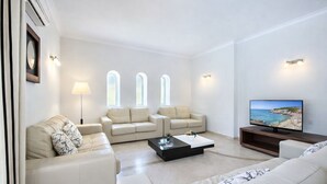 Una sala de estar moderna con un sofá color beige, una mesita de centro y un televisor de pantalla plana.