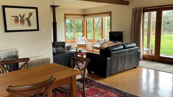 A living room with a fireplace, a sofa, a television, and a dining area with chairs and a table.