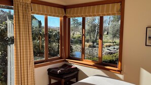 A room with a bed, a bench, and a window with curtains.