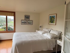 A bedroom with a bed, a nightstand, a lamp, and three framed pictures on the wall.