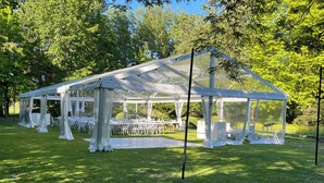 A large, covered outdoor event space with tables and chairs arranged for guests.