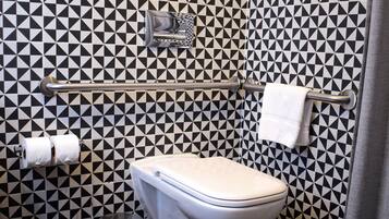 Un baño con un patrón geométrico blanco y negro en el piso, un inodoro, un perchero para toallas y un cubo de basura.