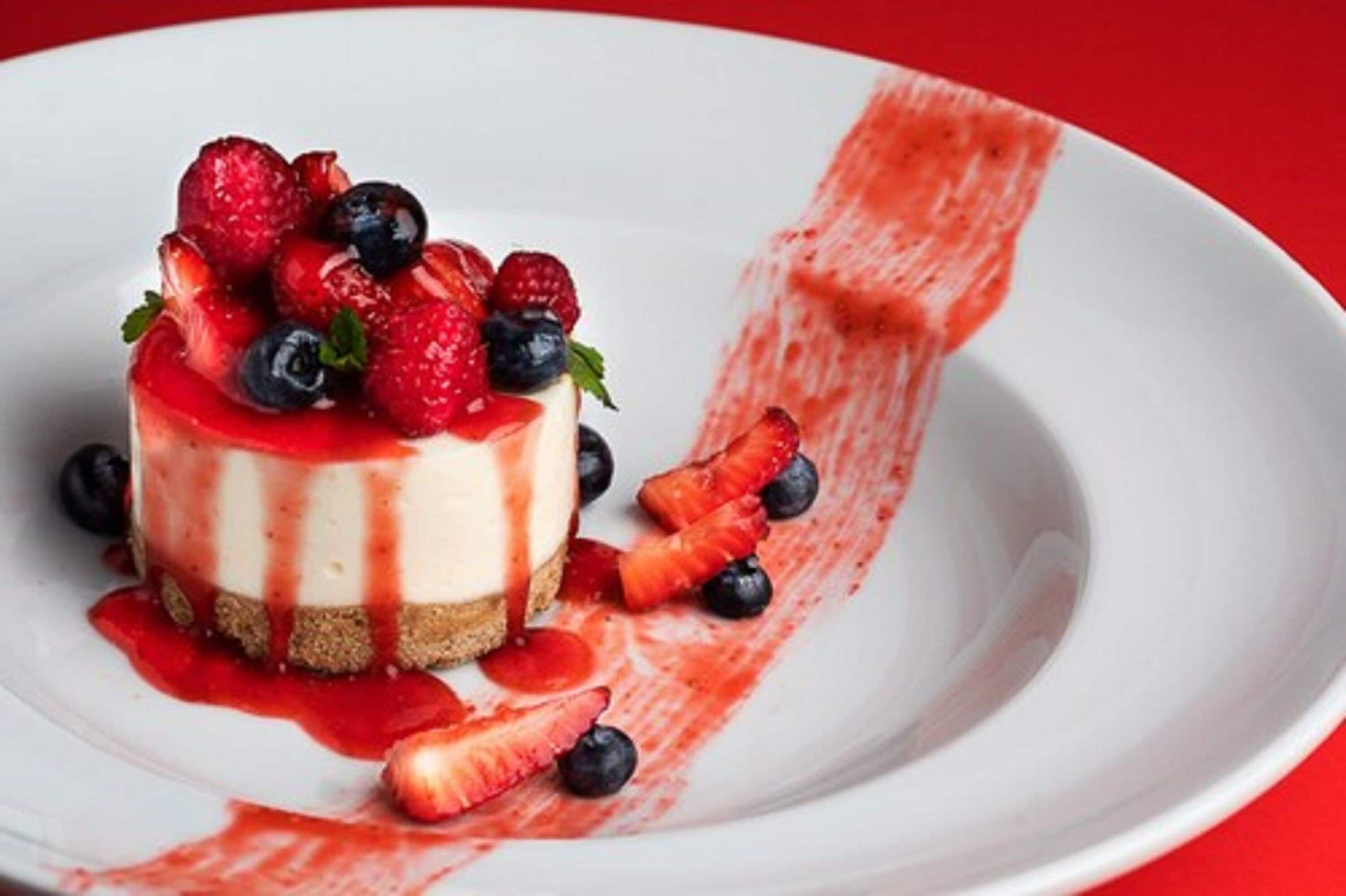 A dessert with strawberries and blueberries on a white plate.