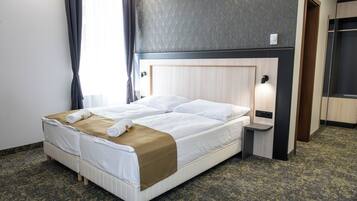 Una habitación de hotel con cama, mesita de noche y espejo.