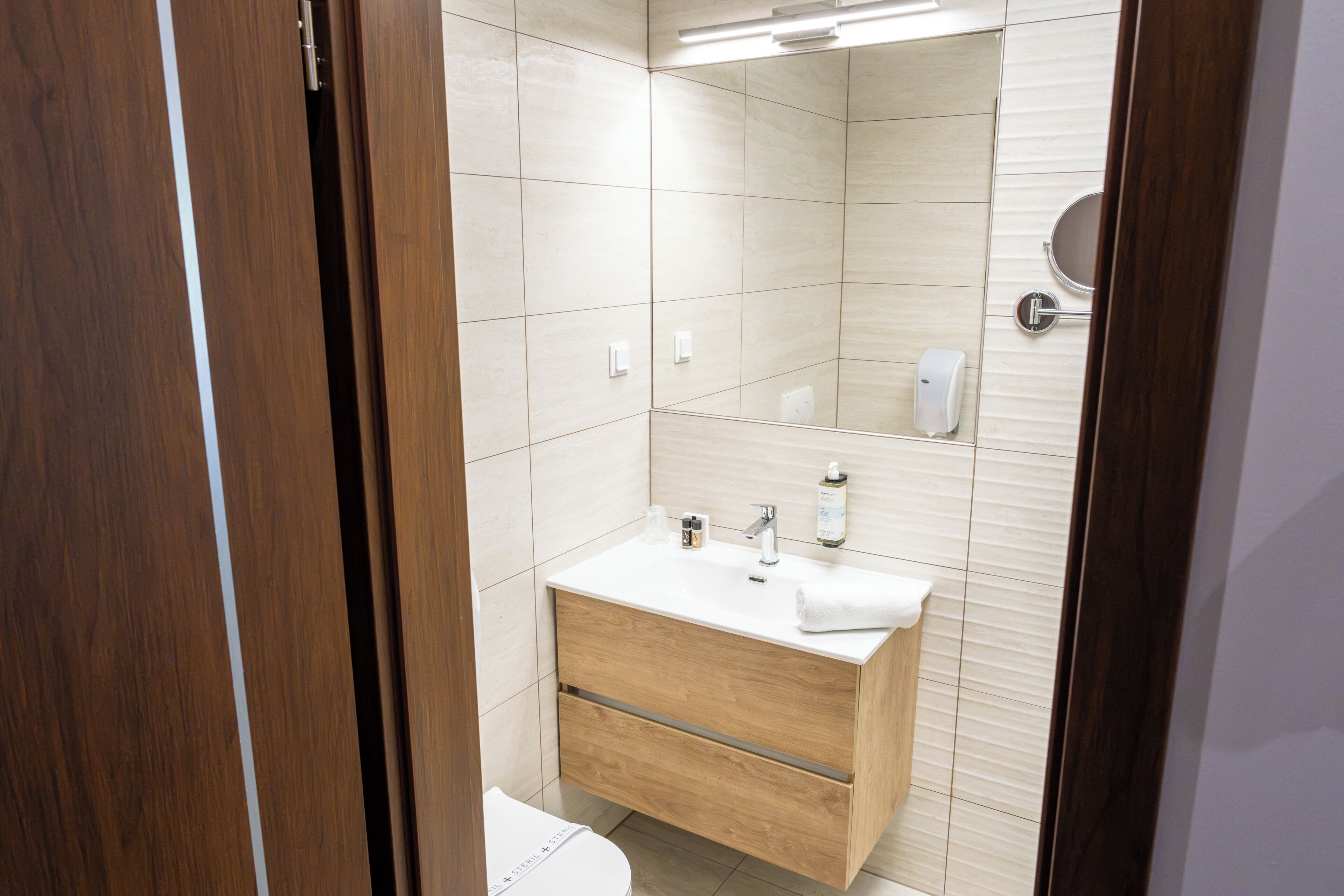 Une salle de bain moderne avec un meuble-lavabo en bois, un miroir et des toilettes.