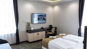 Une chambre d’hôtel équipée d’un lit, d’un bureau, d’une chaise et d’un téléviseur diffusant des informations sur l’hôtel.