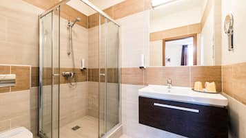 A modern bathroom with a glass-enclosed shower, a white sink, and a dark wood vanity.