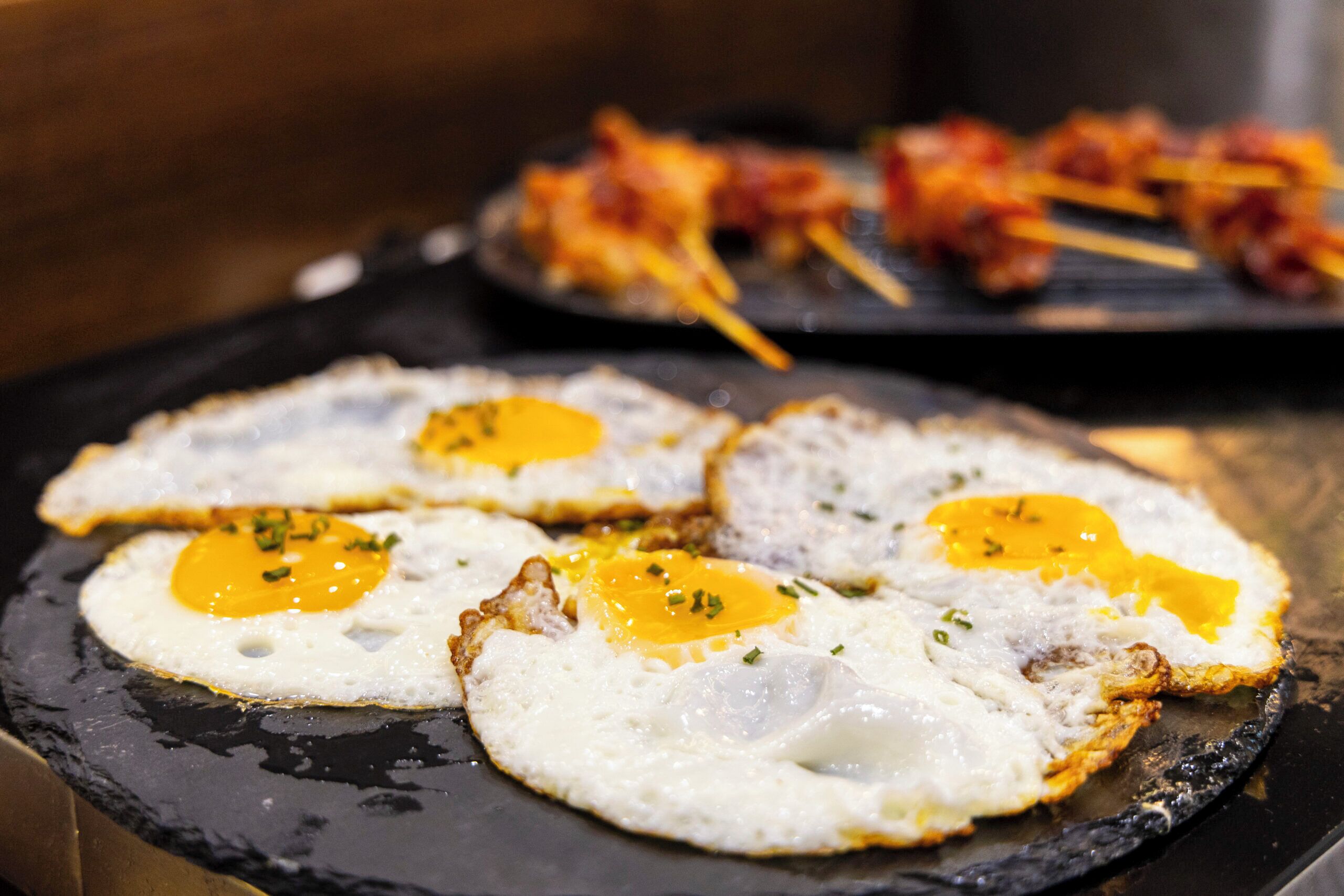 Three sunny-side-up eggs on a black skillet.