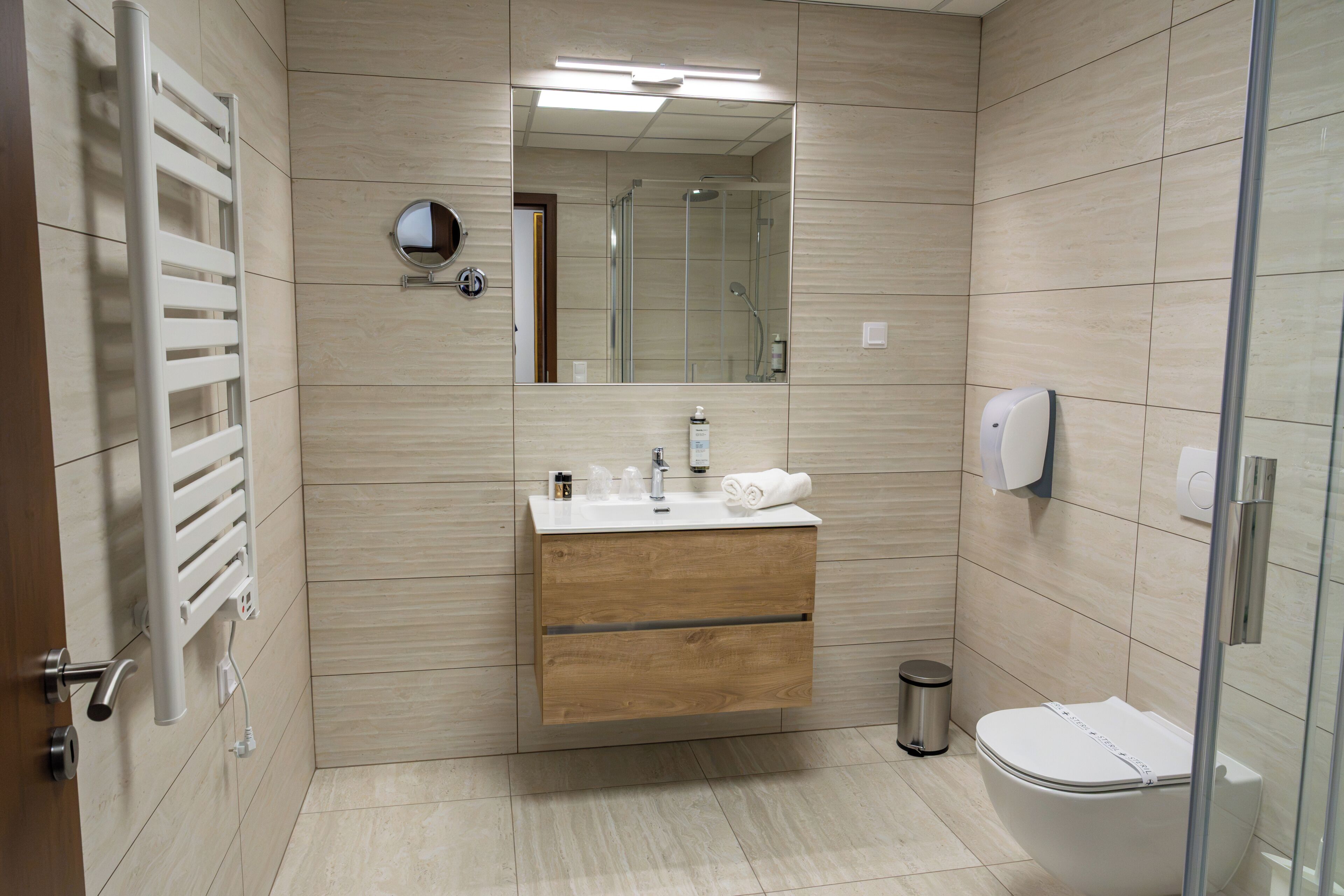 Un baño moderno con un tocador de madera, un espejo, un inodoro y una ducha.