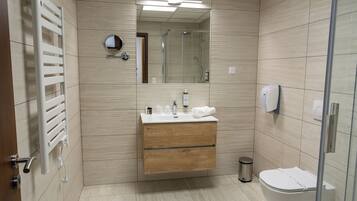Un baño moderno con un tocador de madera, un espejo, un inodoro y una ducha.