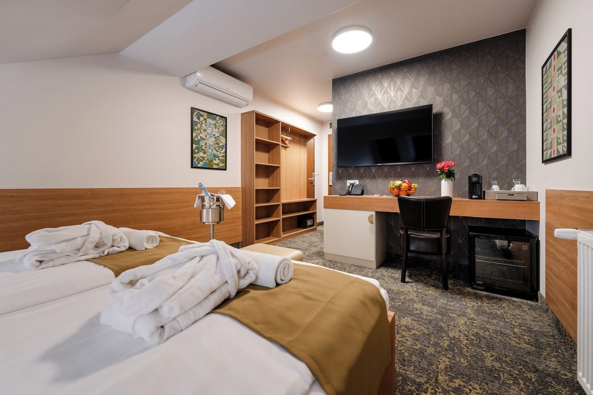 Une chambre d’hôtel avec deux lits, un bureau, une télévision et un minibar.