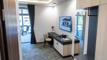 A hotel room with a desk, a chair, a sink, and a large window.