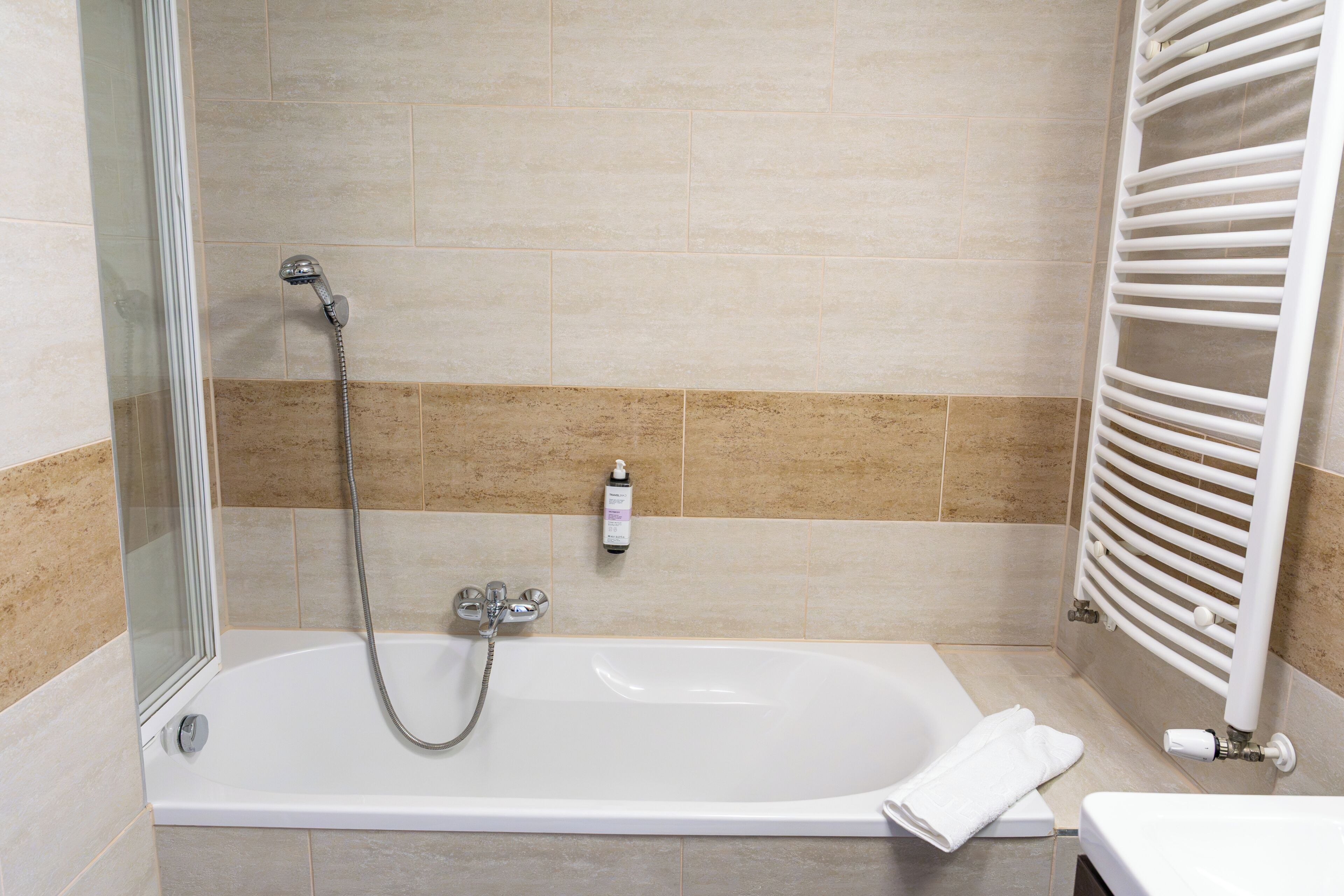 Une salle de bain avec une baignoire, une douche et un porte-serviettes.