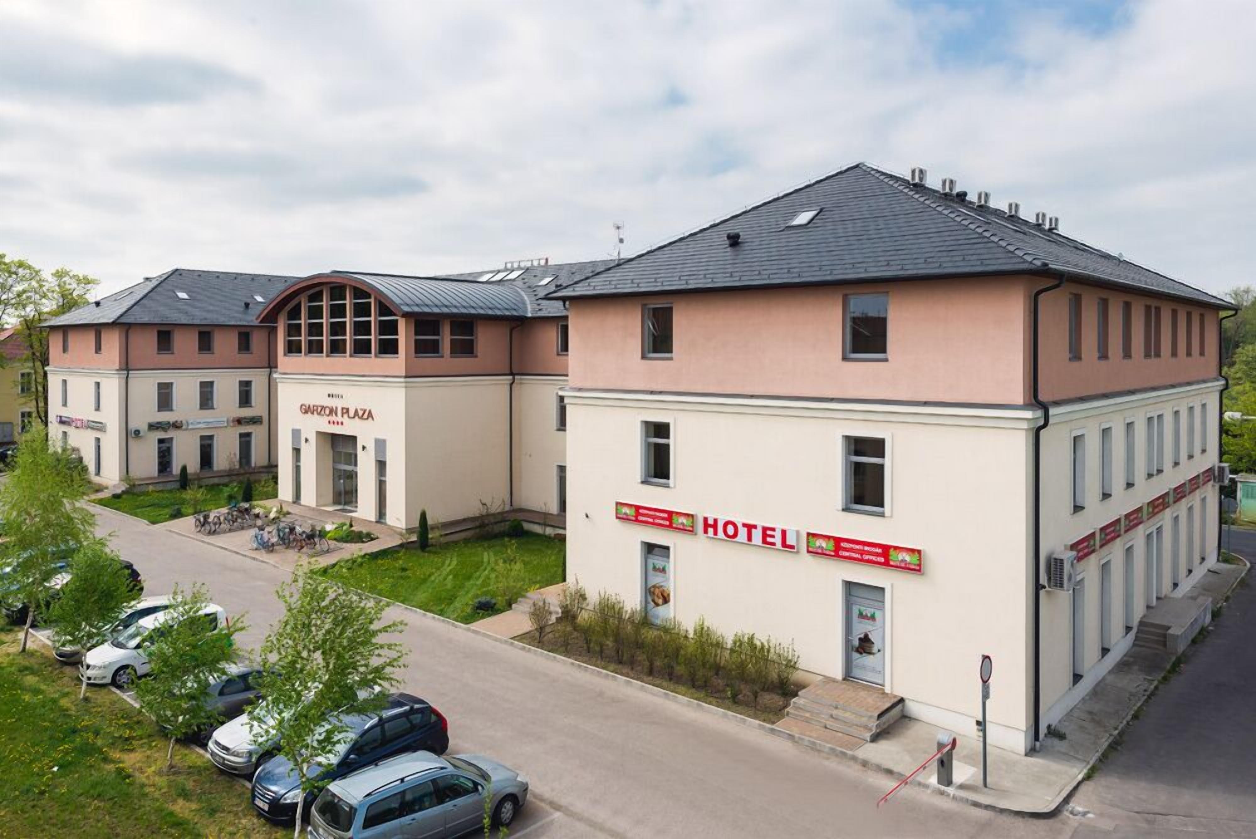 A hotel with a modern design, featuring a prominent 'HOTEL' sign and a 'GARZON PLAZA' sign on the building.