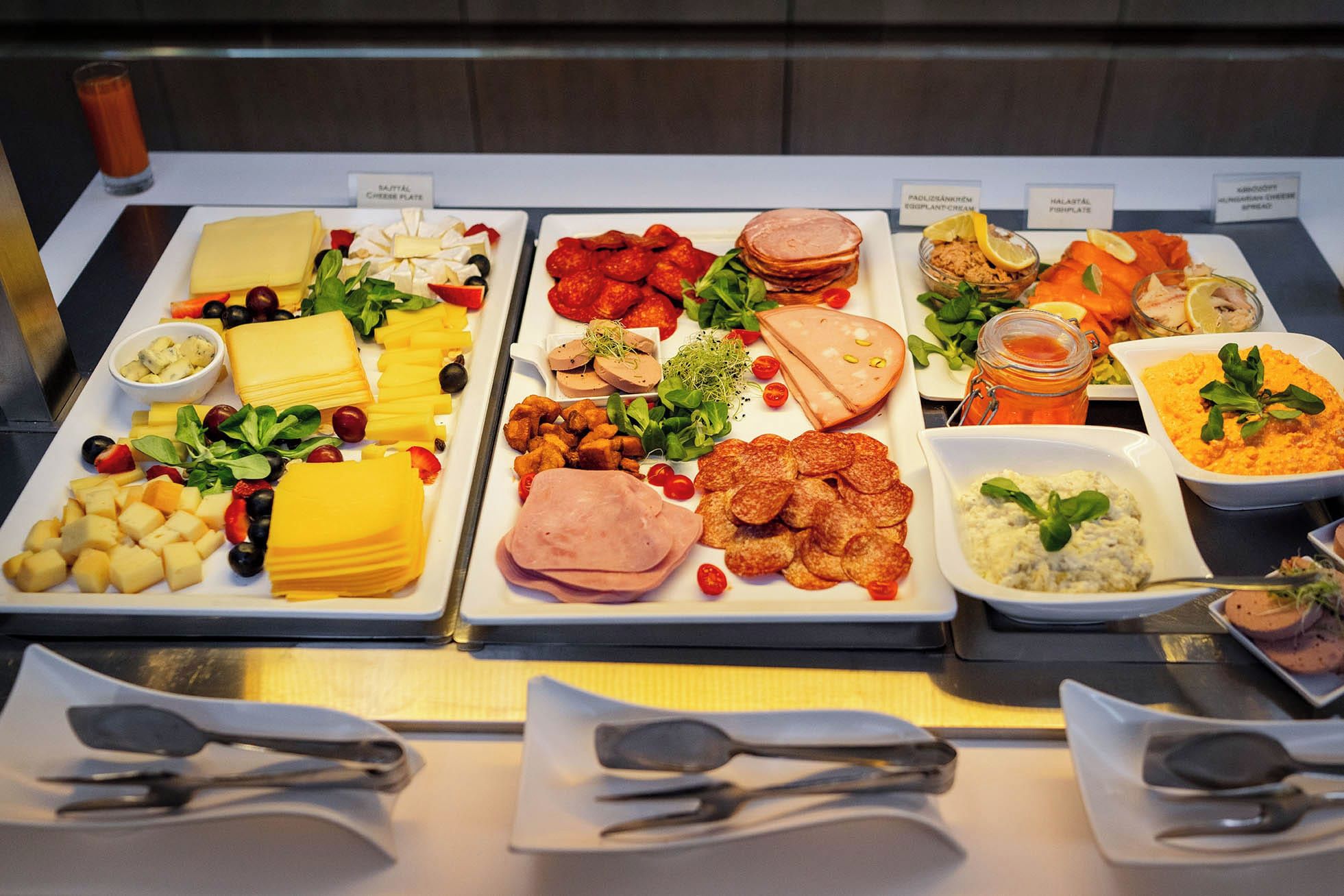 Un bufé con diversas opciones de comida, incluyendo queso, carnes y ensaladas.