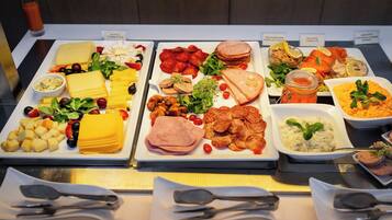 Un bufé con diversas opciones de comida, incluyendo queso, carnes y ensaladas.