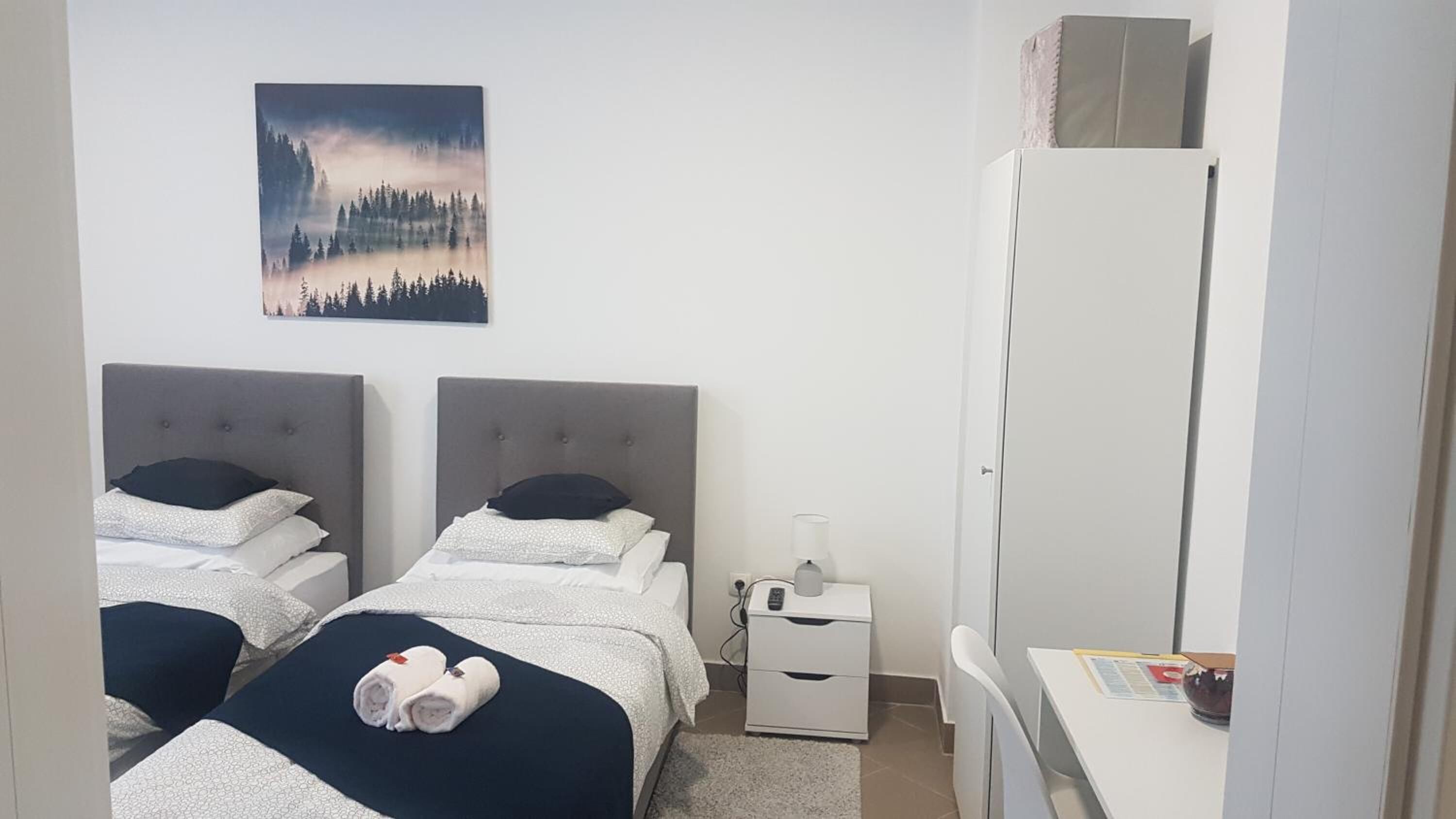 A hotel room with two beds, a nightstand, a desk, and a large mirror.
