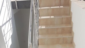 Eine Treppe mit beigen Fliesen, einem Metallgeländer und einer schwarzen Matte am unteren Ende.