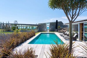 A modern pool area with a clear view of the pool, lounge chairs, and a glass-enclosed structure. - Kina Retreat - Tasman Luxury Estate (Kina Peninsula)