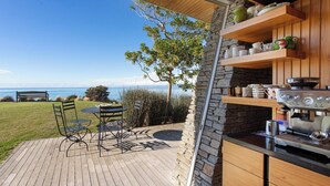 Un patio con una mesa, sillas, un muro de piedra y una cafetera.