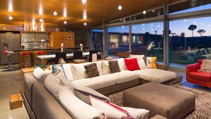 Una sala moderna con un amplio sofá modular, un comedor y una cocina.