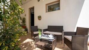 An outdoor seating area with wicker furniture, a glass table, and potted plants. - La Maison-D B&B (Monopoli)