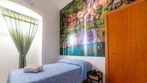 A bedroom with a bed, a nightstand, a door, and a wall mural of a waterfall. - La Maison-D B&B (Monopoli)