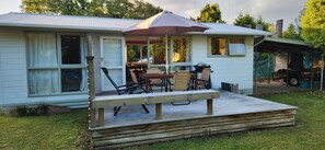 A small house with a porch, a dining table, and chairs.