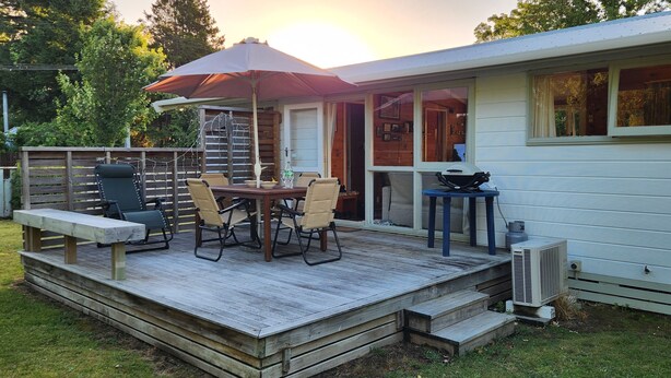 Um terraço com mesa e cadeiras, churrasqueira e área coberta com guarda-sol.