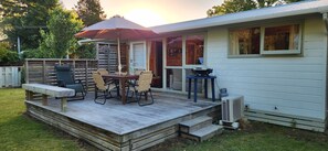 A deck with a table and chairs, a grill, and a covered area with an umbrella.