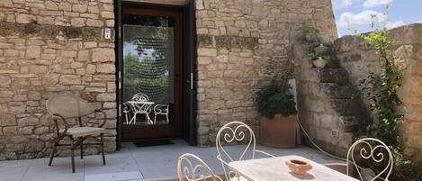 A stone building with a door leading to a covered patio area.