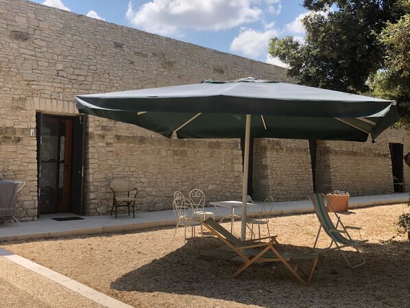 A stone building with a patio area featuring a table, chairs, and an umbrella.