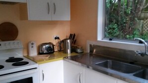 A compact kitchen with white cabinets, a stainless steel sink, and a window overlooking greenery. - Peaceful, sunny, furnished - everything you need. (Johnsonville)