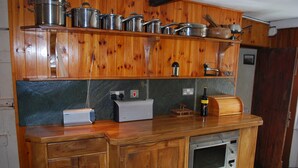 Une cuisine en bois équipée d’un four encastré, d’un grille-pain et de différents ustensiles de cuisine rangés sur des étagères.