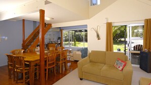 Un vaste espace de vie comprenant une table et des chaises en bois pour la salle à manger, un canapé et un escalier menant à un niveau supérieur.