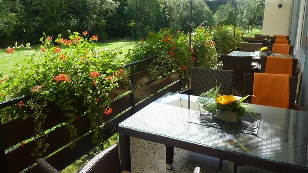 Un patio al aire libre con mobiliario de mimbre, una mesa de vidrio y una sombrilla.