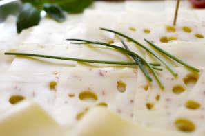 Primer plano de queso en rodajas con hierbas y aceite de oliva.