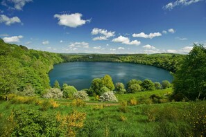 Un lago circular rodeado de exuberante vegetación y un cielo azul despejado.