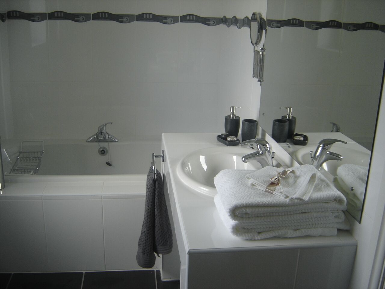 Ein modernes Badezimmer mit einer Badewanne, zwei Waschbecken und einem großen Spiegel.