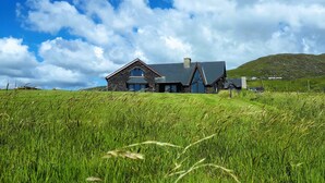 Ein Haus mit Natursteinfassade, geneigtem Dach und einem großen Fenster.