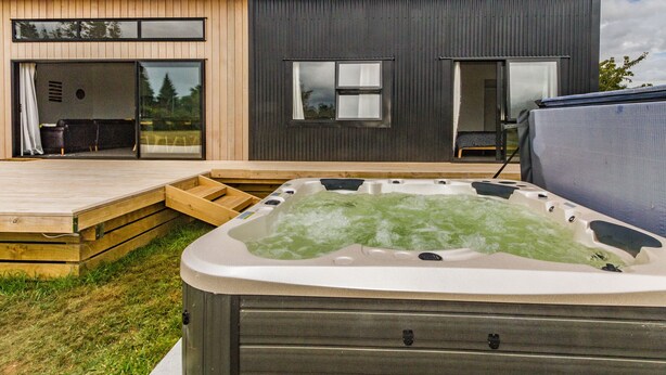 Una casa moderna con un jacuzzi en el patio trasero.