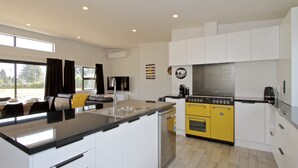 Una cocina moderna con armarios blancos, una estufa amarilla y un ventanal grande.