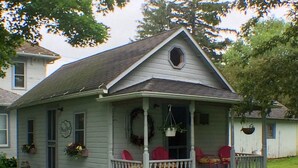 A small, single-story house with a porch, a front door, and a small window. - Taylor Made Bed and Breakfast (Spillville)
